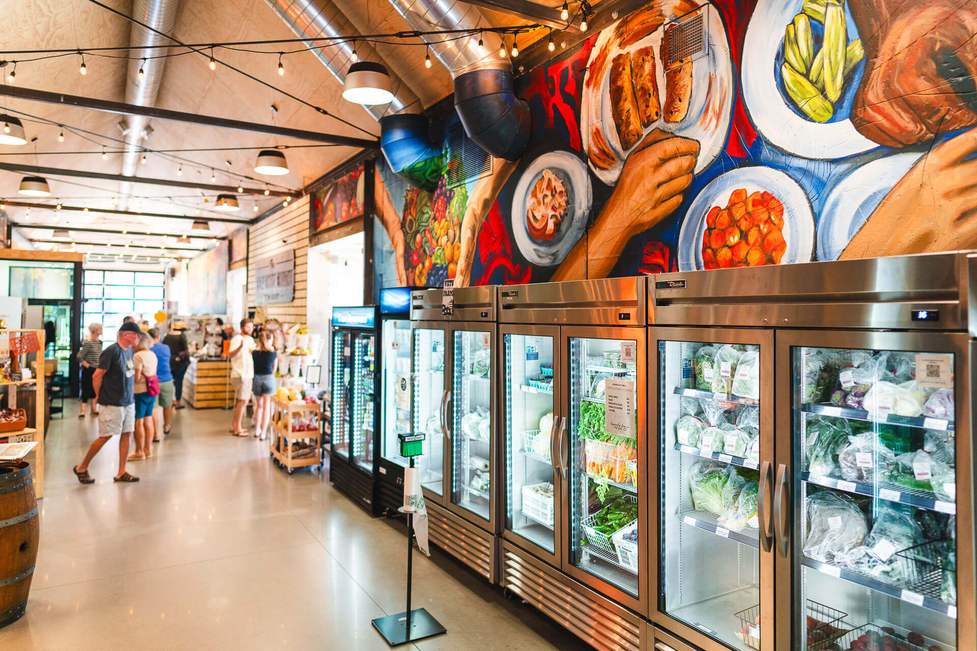 A mural is seen above cases of local food at a market